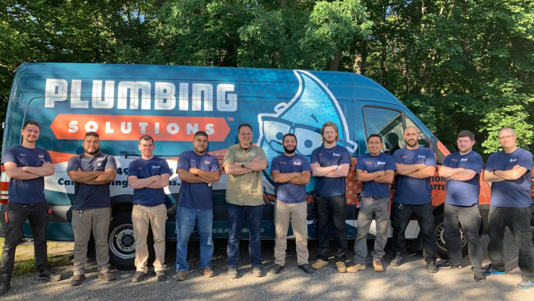 Plumbing Solutions Inc. crew members standing with arms crossed in front of a Plumbing Solutions Inc. truck